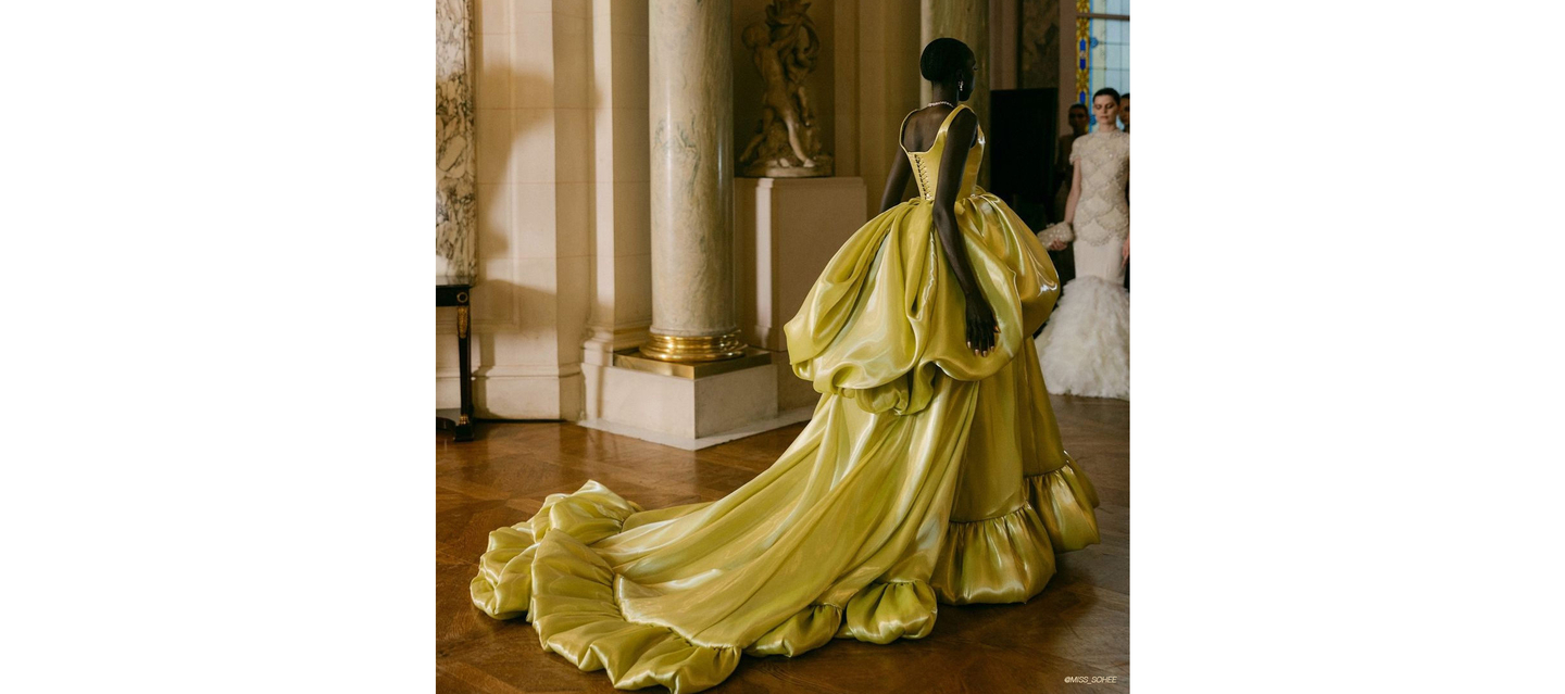 Model in yellow gown embodying fashion week elegance.